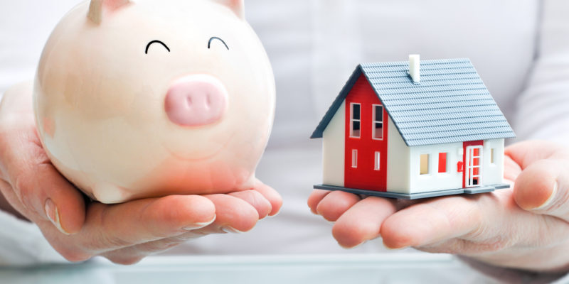 Hands holding a  piggy bank and a house model. Housing industry mortgage plan and residential tax saving strategy